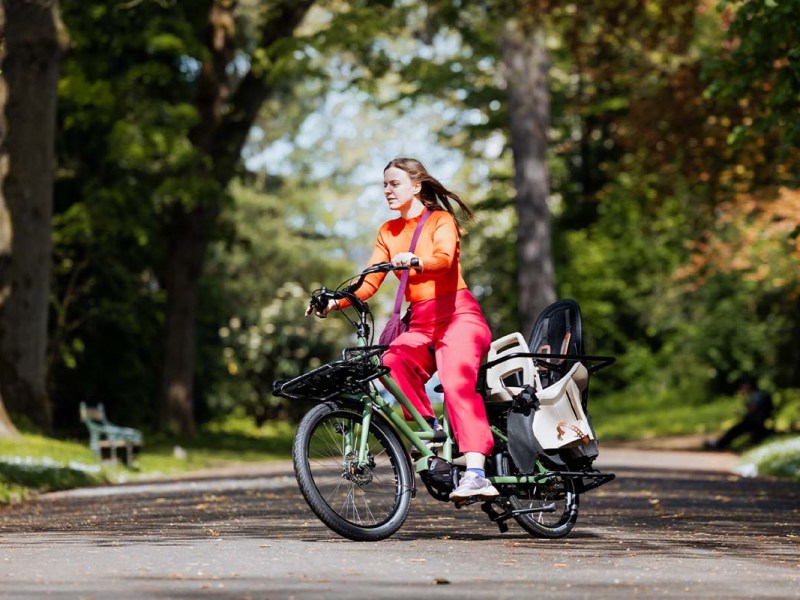 Frau fährt mit einem kompakten Cargo-LE-Bike durch einen Park