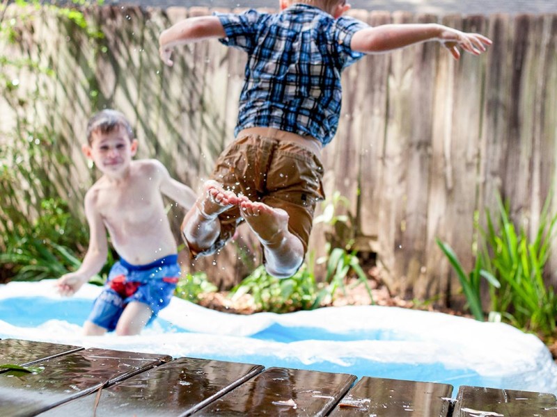 Zwei Kinder spielen in einem Pool im Garten.