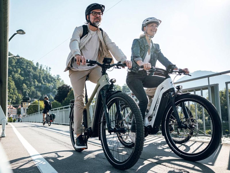 Zwei Personen auf einem E-Bike über eine Brücke.