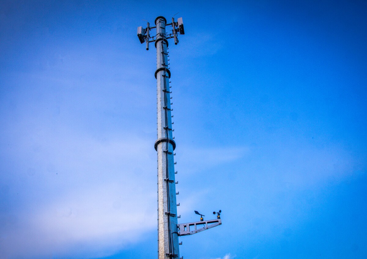 Ein Mobilfunkmast ragt in den blauen Himmel.