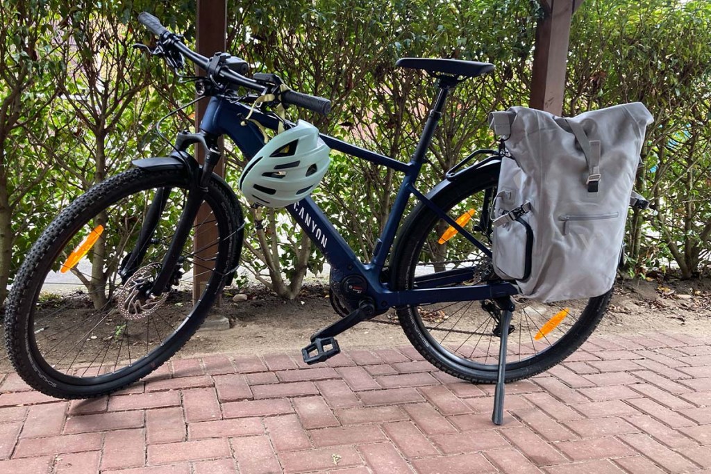 Fahrrad vor einer Hecke stehend, hat eine Fahrradtasche am Gepäckträger