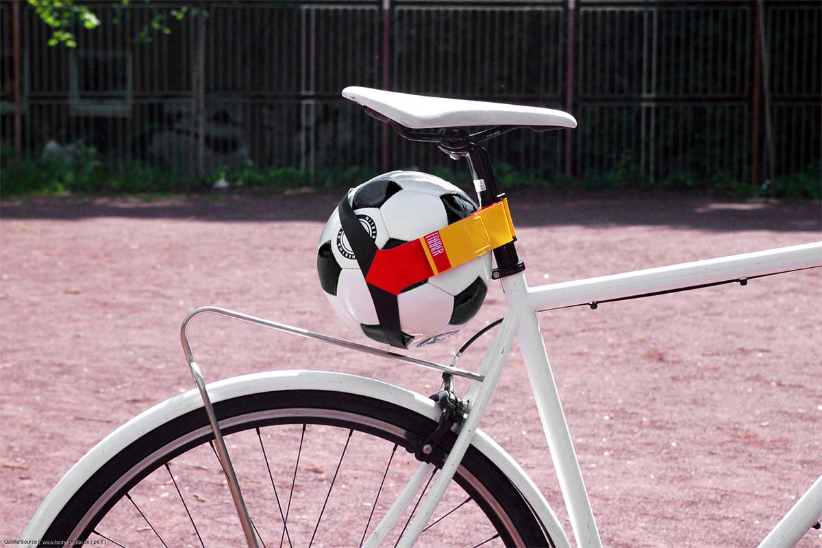 Anschnitt Fahrrad, an dem per Gurt ein Fußball befestigt ist