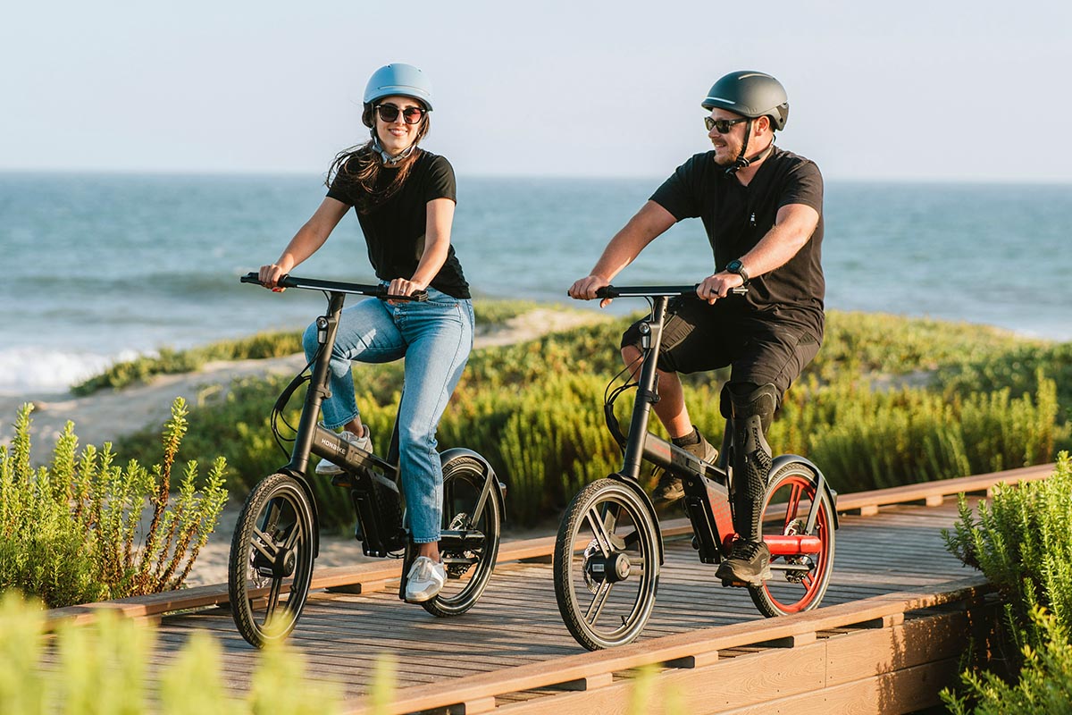 Zwei Personen mit Helm fahren auf einem E-Bike.