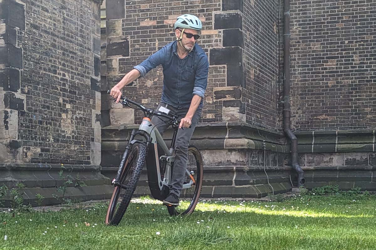 Mann fährt auf einem E-Mountainbike, Kirche im Hintergrund