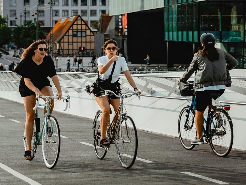 Drei Personen auf einem Fahrrad auf der Straße.