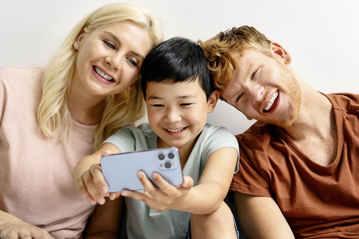 Zwei Erwachsene und ein Kind mit Smartphone in der Hand.