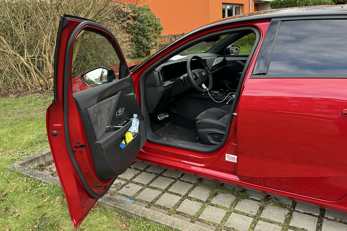 Detailaufnahmen E-Auto Opel Astra Sports Tourer Electric seitliche Ansicht ins Fahrzeuginnere mit geöffneter Fahrertür.