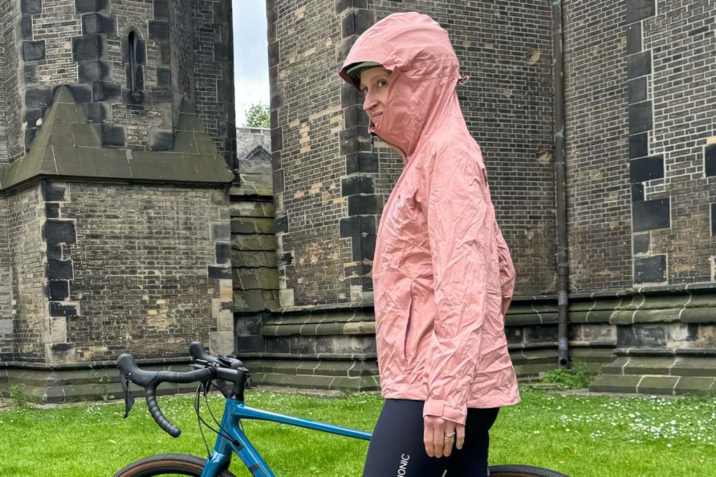 Frau mit Regenjacke, steht neben ihrem Rad