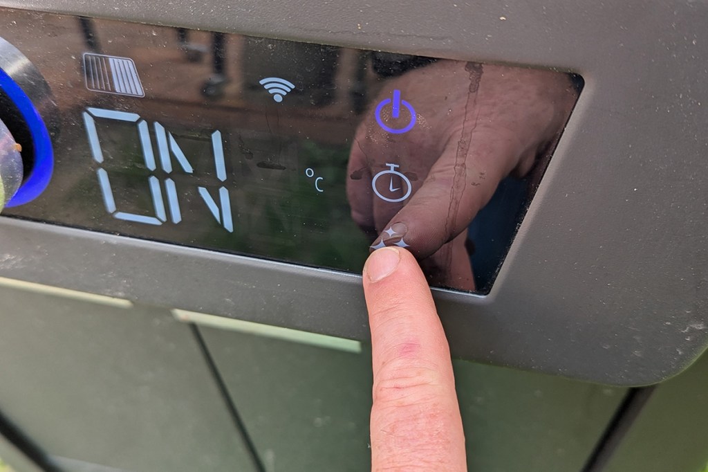 Ein Finger auf dem Selbstreinigungsbutton des Displays