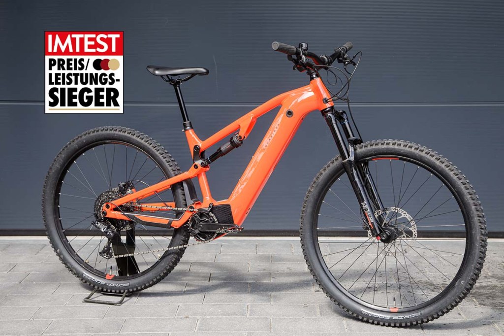 Totale orangenes E-Bike vor einer Wand mit Preis-Leistungs-Sieger-Grafik