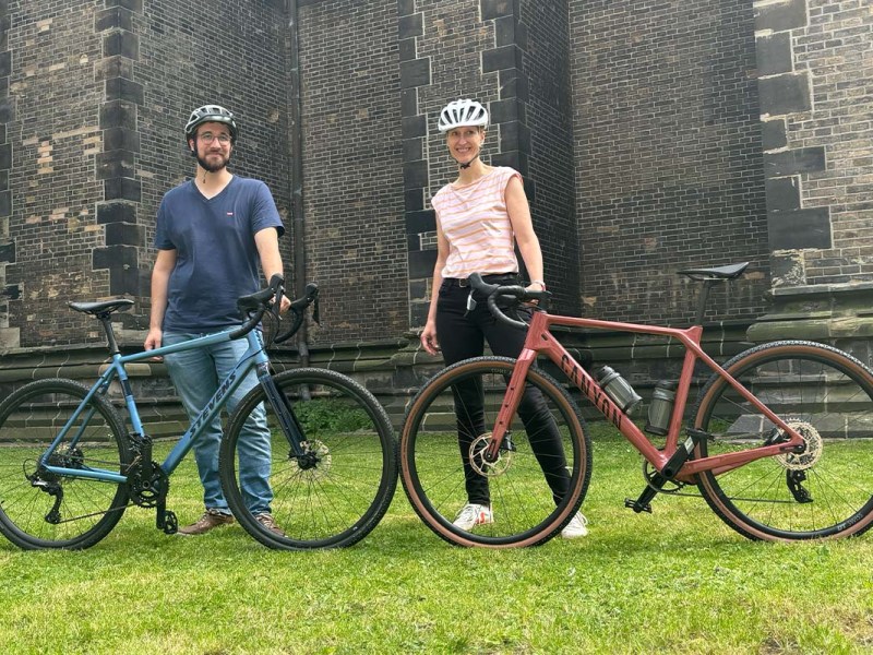 Zwei Gravelbikes stehen sich gegenüber,die jeweils von einer Person, die hinterm Rad steht, festgehalten wird