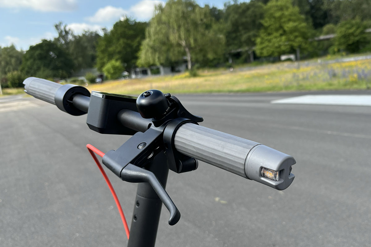 Detailaufnahme eines Lenkers bei einem E-Scooter mit Bremshebel und in den Lenkergriffen versenkten Blickern.