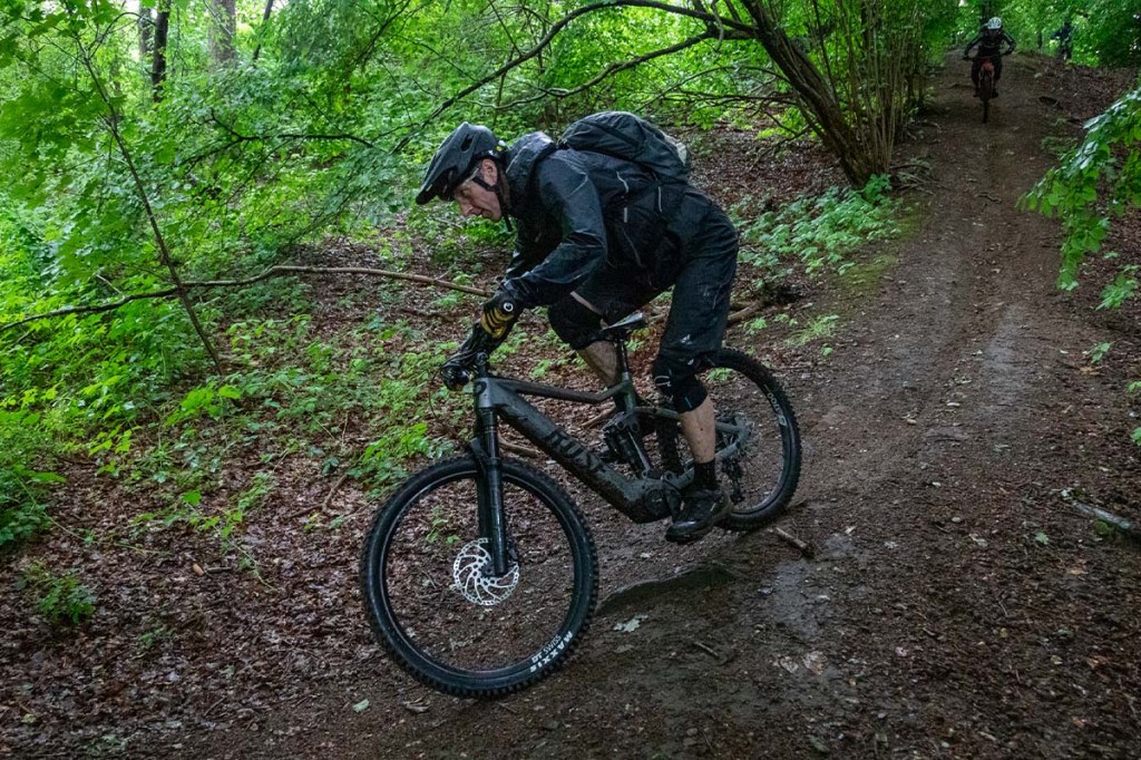 Mann fährt mit einem Mountainbike einen steilen Trail im Wald