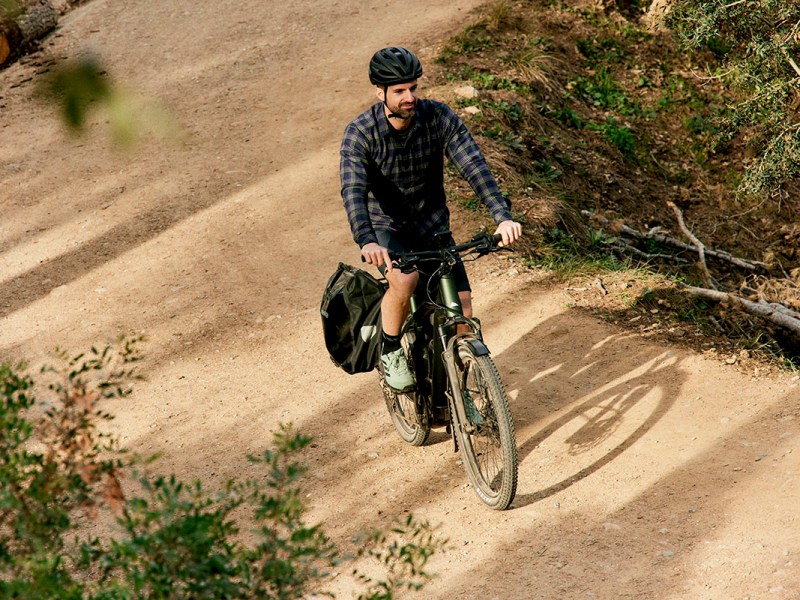 Mann fährt auf Trekking-E-Bike durch eine Parklandschaft.