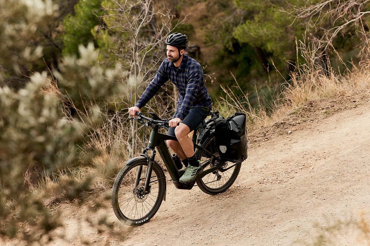 Radfahrer, fährt mit seinem E-Bike über einen Schotterweg in der Natur