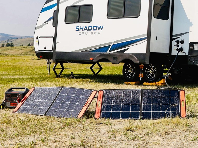 Mobile Solarmodule stehe auf dem Boden vor einem Camper.