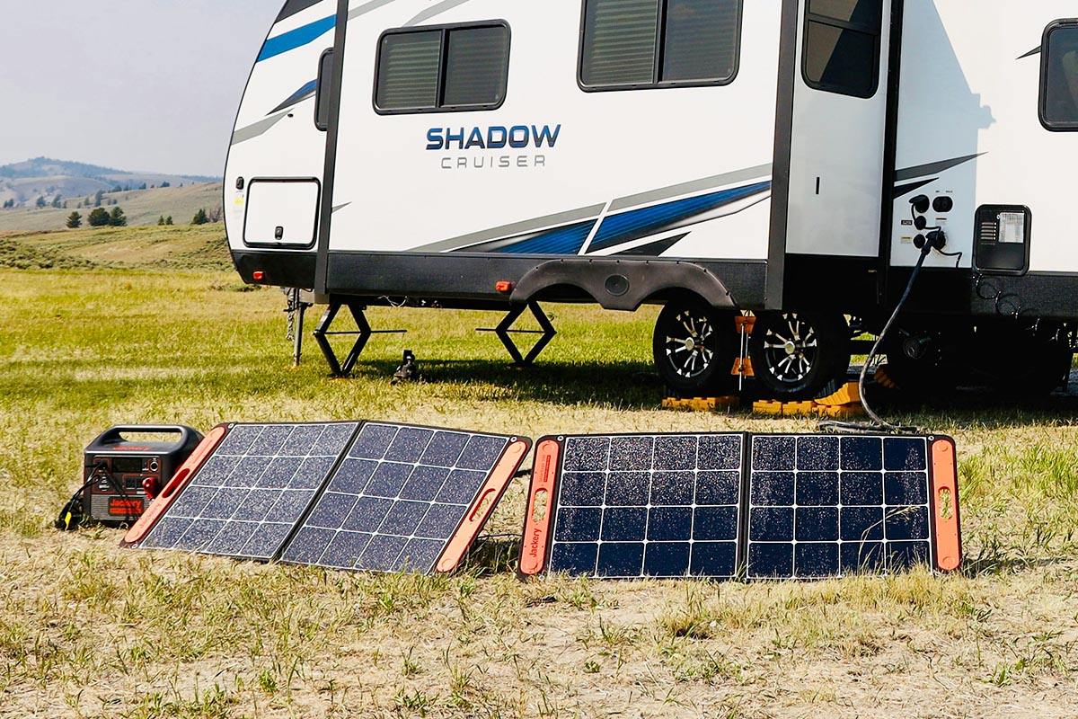 Mobile Solarmodule stehe auf dem Boden vor einem Camper.