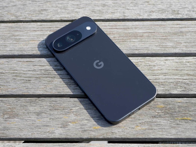 Das Smartphone Google Pixel 9 liegt mit dem Display nach unten auf einem Holztisch.