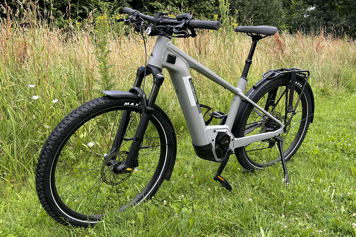 Graues Trekking-E-Bike Canyon Pathlite:ON 6 SUV steht in schräger Ansicht vor einem Weizenfeld am Wegesrand.