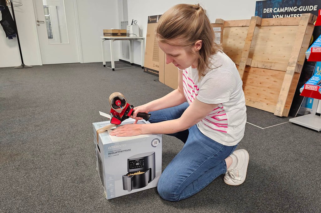 Eine Frau packt eine Heißluftfritteuse in ein Paket.