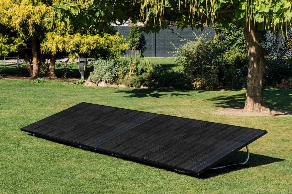 Zwei Solarpanels mit Aufstell-Halterung in einem grünen Garten.