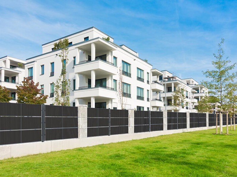 Ein weißes Wohnhaus mit grünem Rasen und einem Solar-Zaun davor.