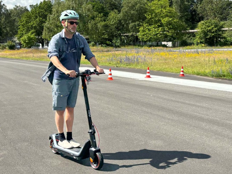 Mann fährt mit einem E-Scooter über eine Straße