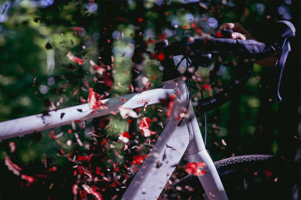 Nahaufnahme weißes Gravel-E-Bike, HErbstblätter wirbeln um den Rahmen