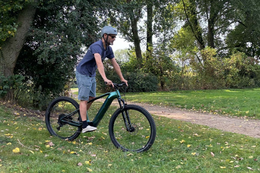 Mann fährt auf einem E-Mountainbike durch einen Park
