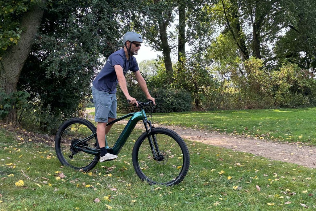 Mann fährt auf einem E-Mountainbike durch einen Park