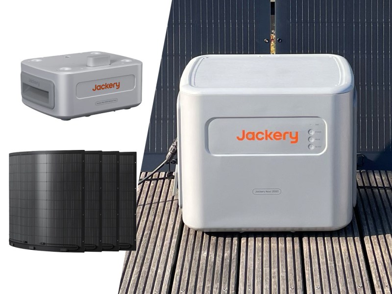 Der Navi 2000 Speicher von Jackery auf Holzplanken mit Solarpanels im Hintergrund. Links zudem flexible Solarpanels und ein Zusatz-Akku auf weißem Grund.