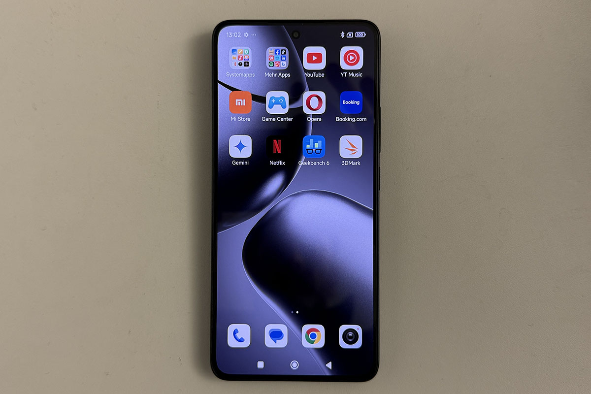 Smartphone Xiaomo 14T in frontaler Ansicht mit eingeschaltetem Display, das unterschiedliche App-Symbole anzeigt. Das Gerät liegt auf einer weißen Tischplatte.