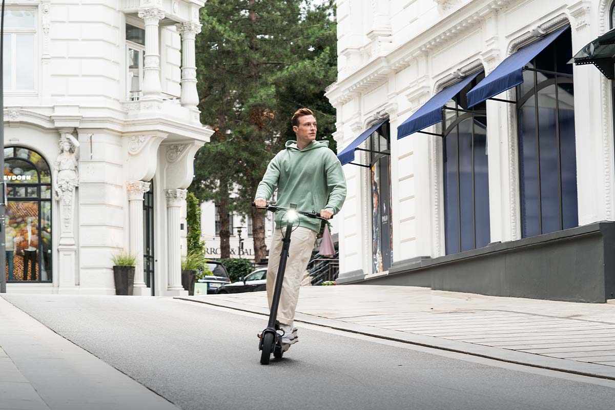 Mann fährt mit einem E-Scooter eine Straße entlang