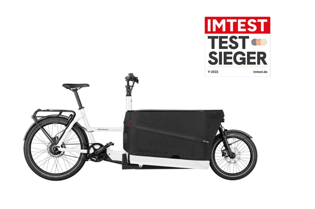 weiß-schwarzes Cargo-E-Bike von der Seite, dazu Testsieger-Siegel