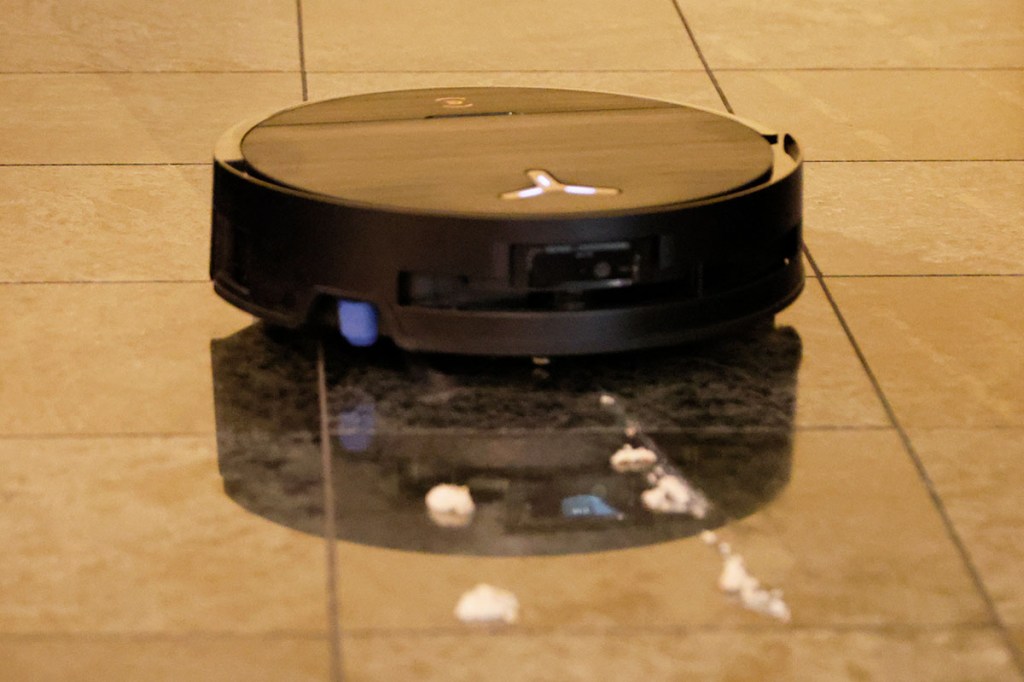 Der Ecovacs Deebot X9 Pro Omni auf Fliesenboden mit Testschmutz vor sich.