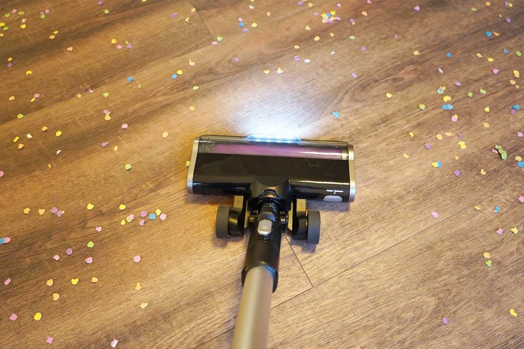 Die Bodendüse vom Eureka Stylus Elite von oben mit eingeschaltetem LED-Licht. Drumherum liegt Konfetti.