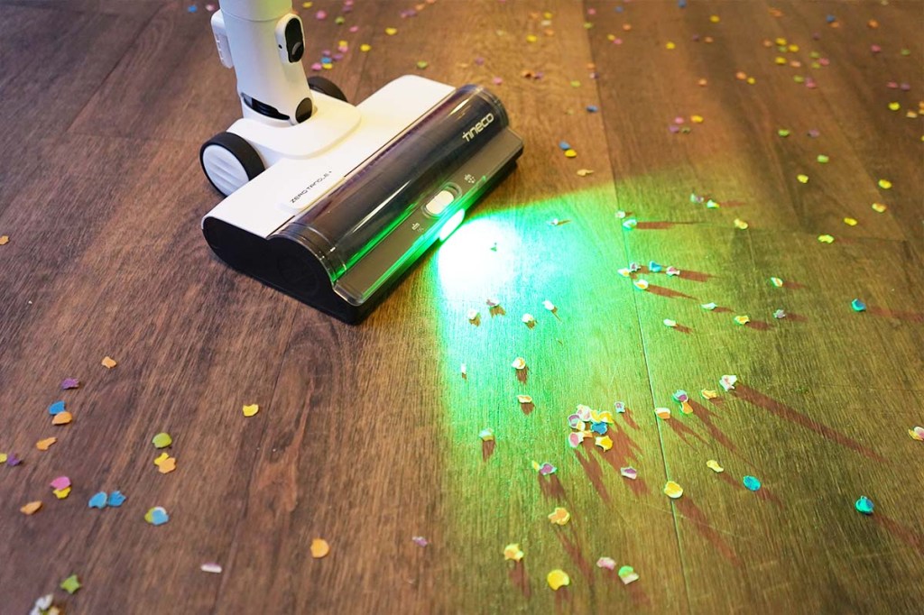 Die Bodendüse vom Tineco-Akkusauger von der Seite mit eingeschaltetem LED-Licht. Drumherum liegt Konfetti.