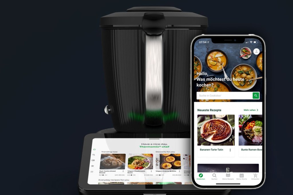 Thermomix TM7 im Hintergrund, vorne ein Smartphone mit geöffneter Cookidoo-APp