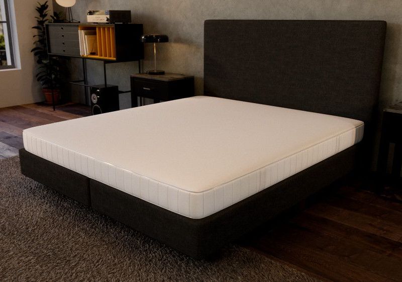 Matratze liegt auf einem Bett. Im Hintergrund ist ein Schlafzimmer erkennbar