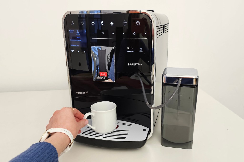 Melitta Kaffeevollautomat mit einer Tasse und einer Hand davor
