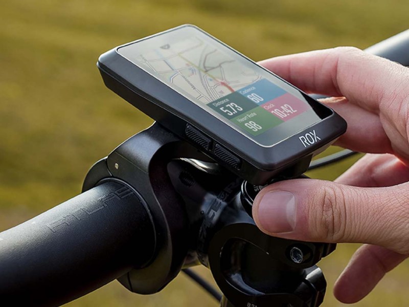 Nahaufnahme Navi an einem Fahrradlenker, das von einer Hand festgehalten wird