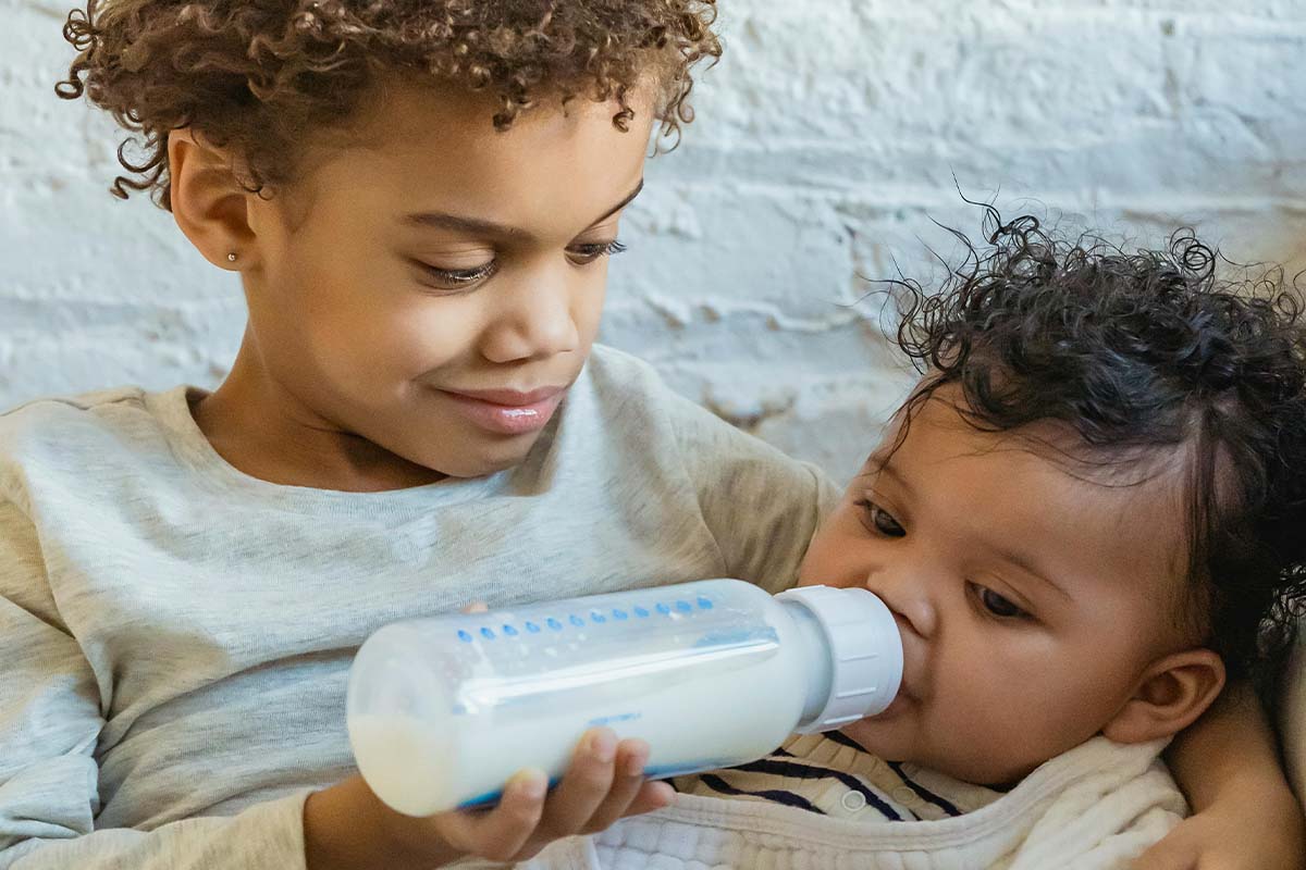 Ein Kind gibt einem Baby die Flasche