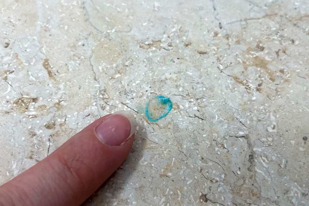 Ein Finger zeigt auf einen Schnmutzrand auf einem Steinboden.