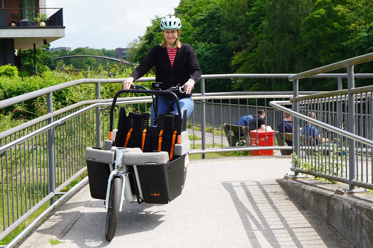 Frau fährt mit einem Cargo-E-Bike über eine Brücke