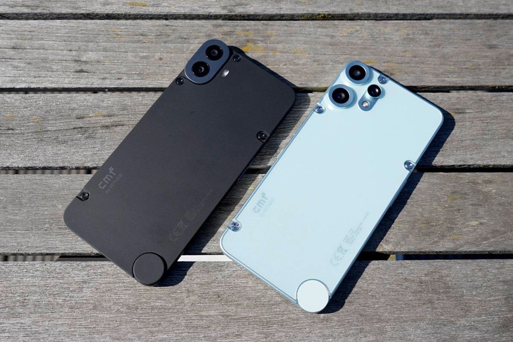Die Smartphones Smartphone CMF Phone 2 Pro und Phone 1 liegen nebenein ander auf einem Holztisch.