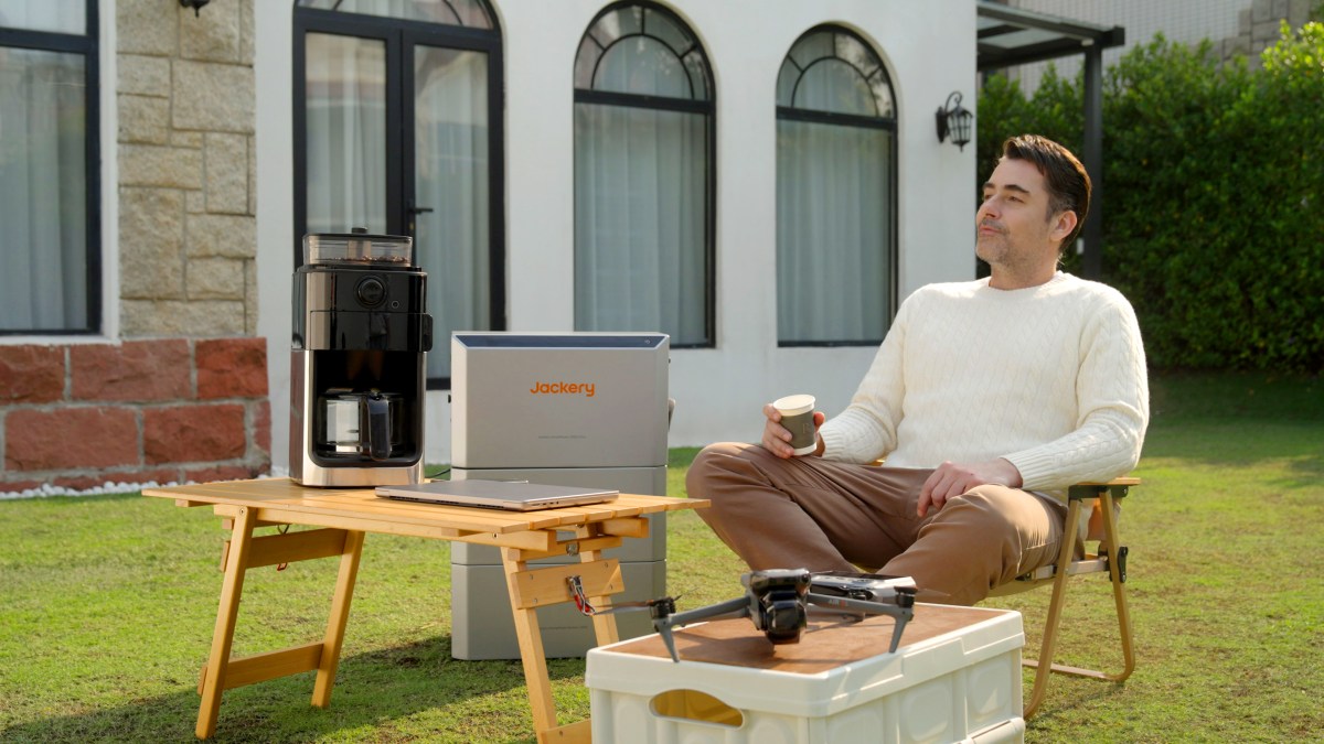 Mann sitzt im Garten vor der Jackery HomePower 2000 Ultra.