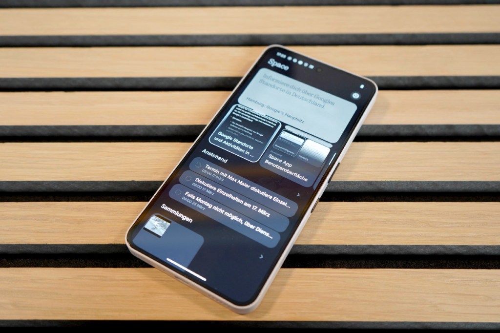 Das Mittelklasse-Smartphone Nothing Phone (3a) liegt mit eingeschaltetem Display auf einem Holztisch.
