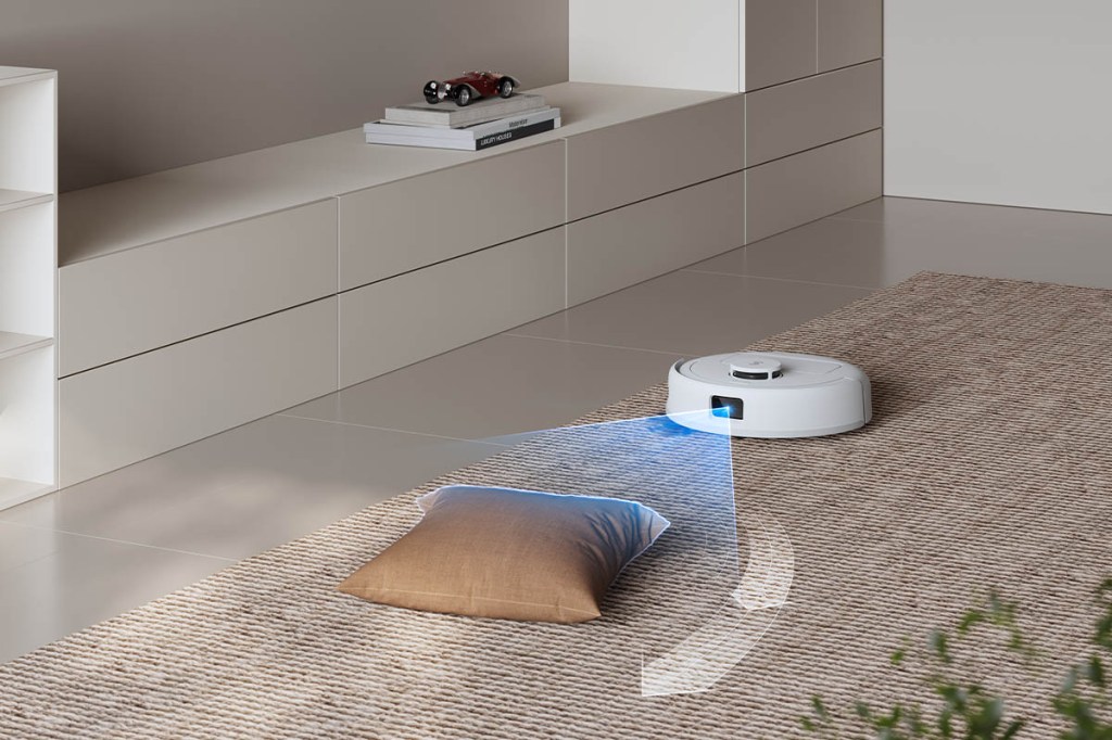 Der Deebot mini in einer Wohnumgebung direkt vor einem Kissen. Blaue Linien verdeutlichen den Scan-Prozess des Roboters, um Hindernisse zu erkennen.