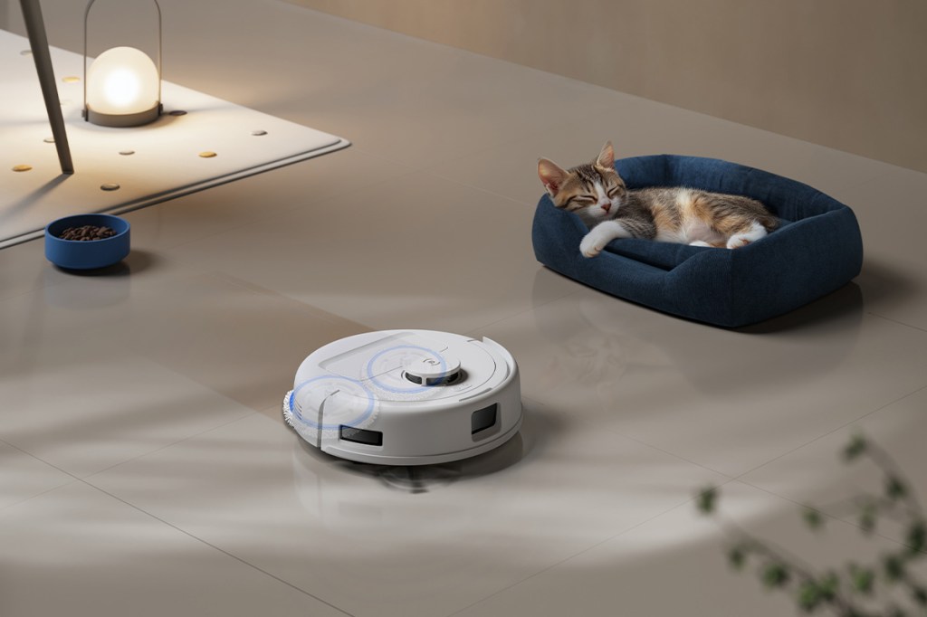 Der Deebot mini saugt neben in einer Wohnumgebung direkt neben einer schlafenden Katze.