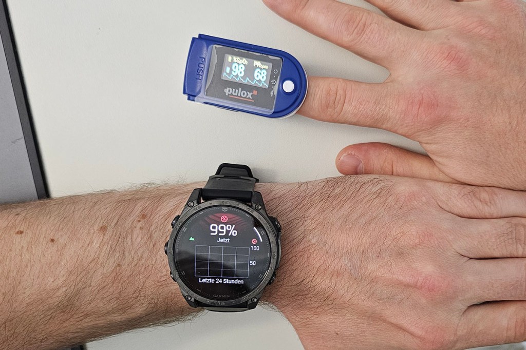 Smartwatch an Arm und Blutsauerstoffmessgerät an Finger
